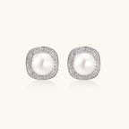 Rhodium-plated sterling silver stud earrings with round freshwater pearls surrounded by geometric crystal halos on cream background.