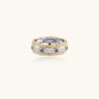 Two-tone ring with brushed silver center, gold beaded edges, and blue zirconia stones on white background.