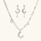Mixed-metal jewelry set featuring layered necklaces with crescent moon pendant and pearl beads, plus matching star-drop earrings.