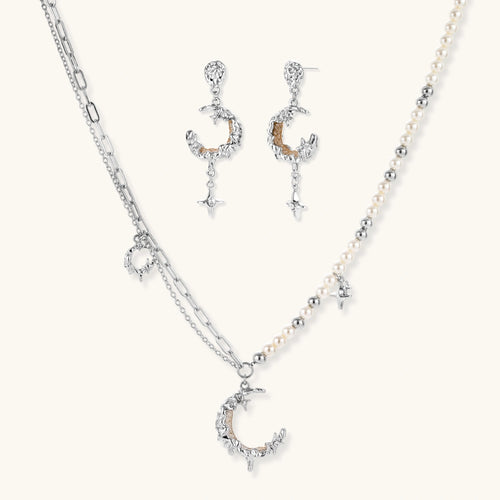 Mixed-metal jewelry set featuring layered necklaces with crescent moon pendant and pearl beads, plus matching star-drop earrings.