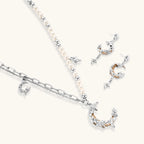 Mixed-metal jewelry set featuring layered necklaces with crescent moon pendant and pearl beads, plus matching star-drop earrings.