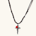 Gothic cross pendant with red enamel rose and thorn details on adjustable brown cord necklace against white background.