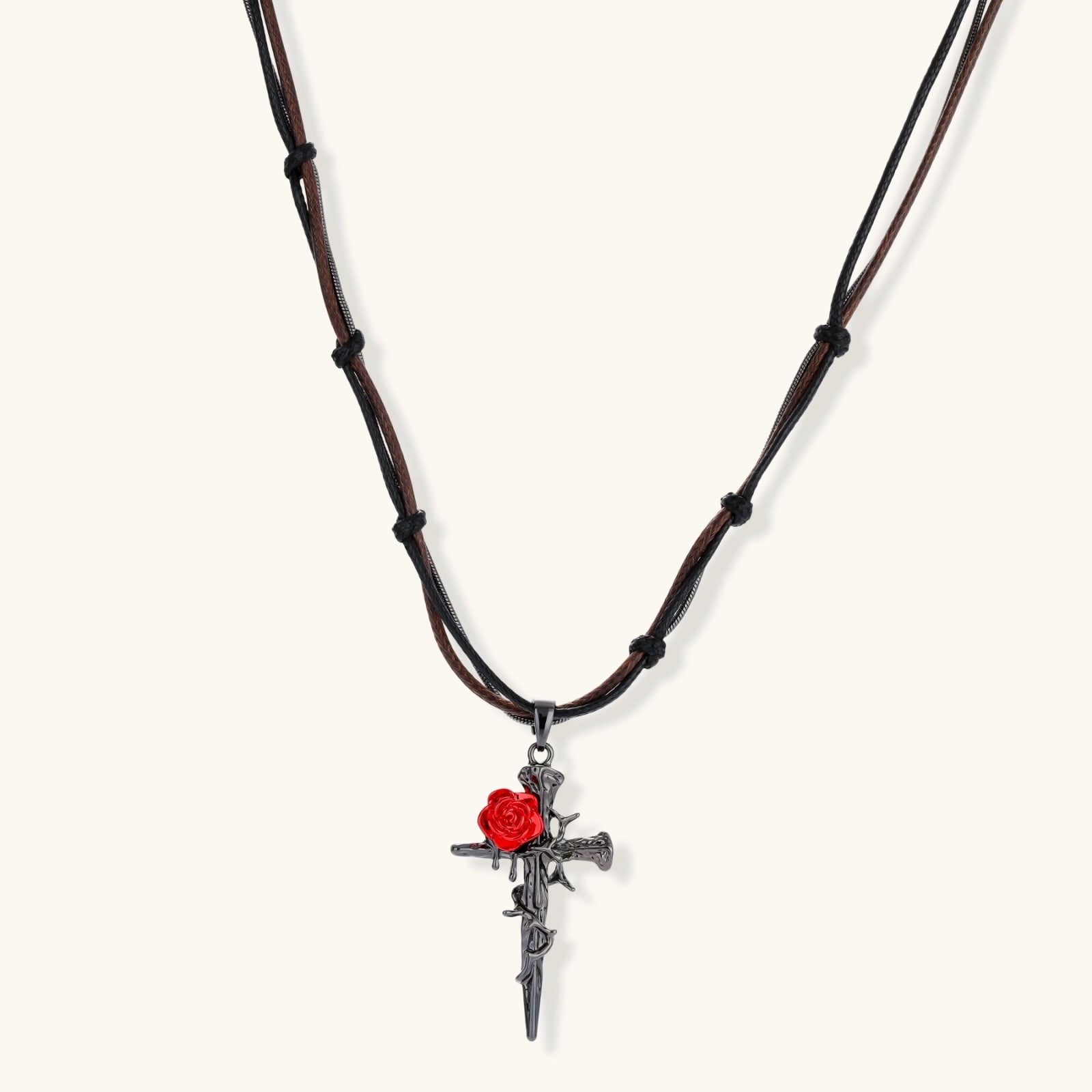 Gothic cross pendant with red enamel rose and thorn details on adjustable brown cord necklace against white background.