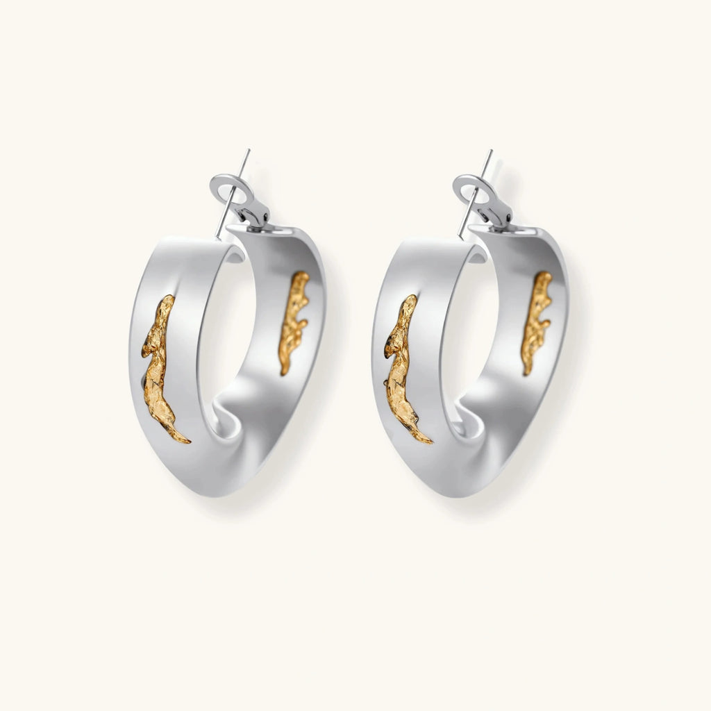 Artistic jewelry set featuring curved silver pendant with gold veining on black cord plus matching asymmetrical hoop earrings