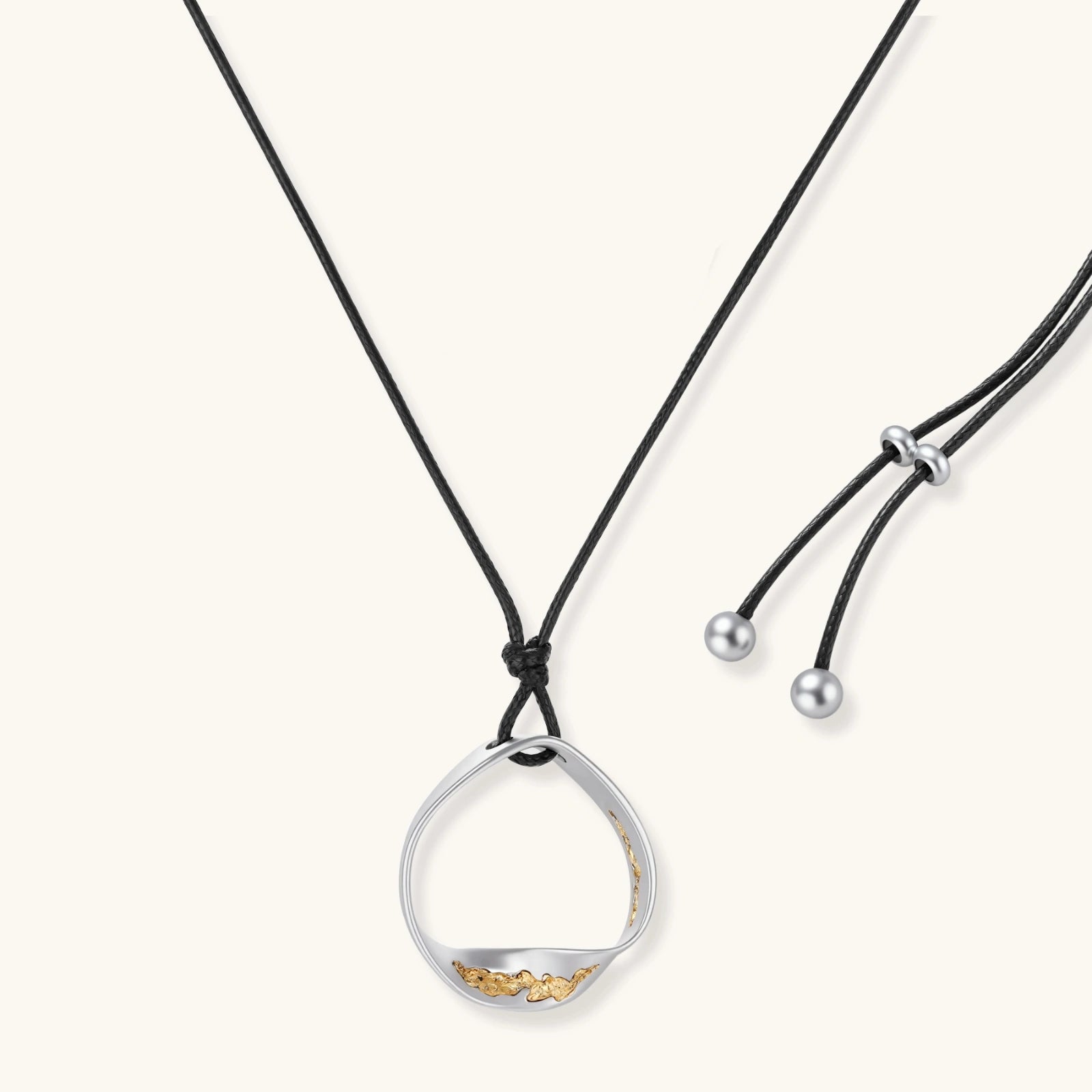 Artistic jewelry set featuring curved silver pendant with gold veining on black cord plus matching asymmetrical hoop earrings