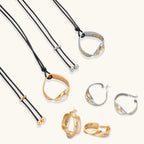 Artistic jewelry set featuring curved silver pendant with gold veining on black cord plus matching asymmetrical hoop earrings