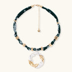 Adjustable necklace with black paisley fabric cord, gold metal spacers, and clear twisted pendant on cream background