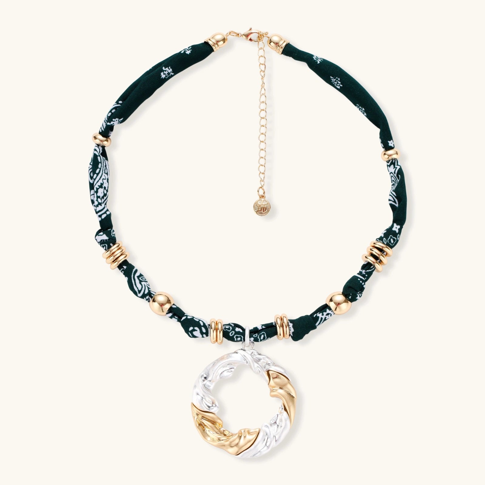 Adjustable necklace with black paisley fabric cord, gold metal spacers, and clear twisted pendant on cream background