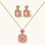 Ornate gold-plated jewelry set with rose pink zirconia center stones and crystal accents on cream background.