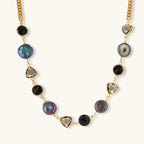 18k gold-plated chain necklace featuring lustrous baroque pearls, black onyx rounds, and smoky quartz triangular stones on white background.