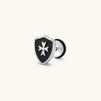 Silver stainless steel shield-shaped stud earring with black enamel and raised Maltese cross, rubber-secured backing.