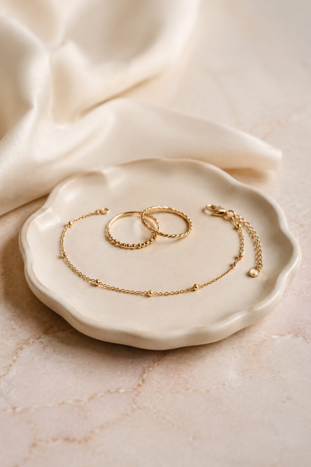 Delicate gold rings and bracelet on an ivory jewelry dish